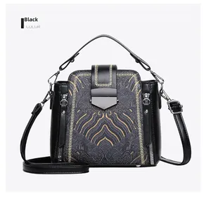 Detailed view of black faux leather bag with gold wave embroidery and top handle