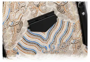Detailed view of vintage embroidery and matte black metal buckle on a textured handbag