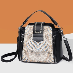 Elegant black leather handbag with traditional embroidery and detachable strap shown in front view