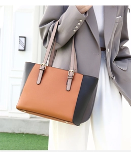 Vista lateral del bolso tote grande naranja y negro combinado con un traje gris formal