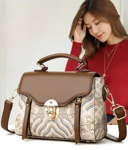 Close-up of vintage brown leather handbag featuring textured embroidery and gold metal lock
