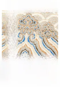 Detail of blue and orange cloud pattern embroidery with a brown leather flap and metal lock