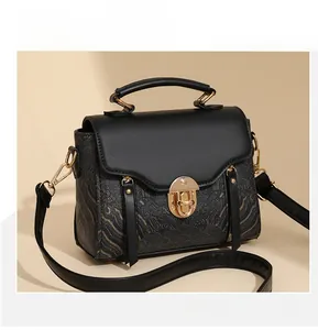 Detail of black crossbody bag with golden landscape print and elegant metal twist lock