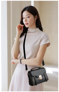 Detailed side view of black square handbag with golden texture and metallic twist lock