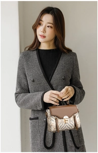 Detail of elegant patterned handbag with brown leather flap and gold twist lock closure