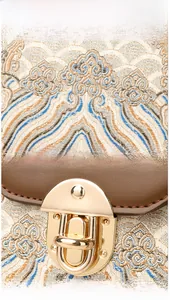 Detail of elegant embroidered fabric with golden twist lock on a vintage shoulder bag