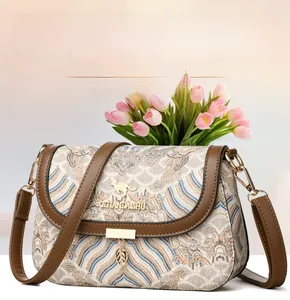 Detail view of ethnic cloud pattern fabric and golden kangaroo logo on brown crossbody bag