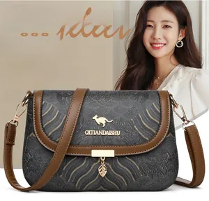 Detail of crossbody bag with golden wave pattern, kangaroo logo, and leaf pendant