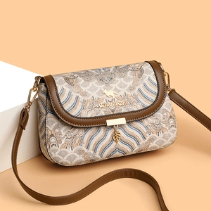 Ethnic embroidered crossbody bag with wave patterns and leaf pendant shown at a 45-degree angle
