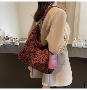 Dettaglio della grande borsa tote leopardata con manici in pelle rossa e mini bustina