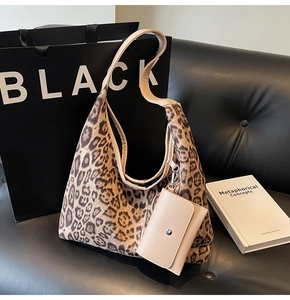 Dettaglio della borsa leopardata con un piccolo portamonete su sfondo in pelle nera