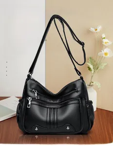 Détail du sac bandoulière en cuir noir souple avec trois fermetures éclair argentées