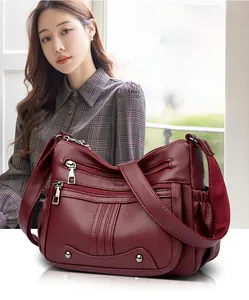 Détail du sac bandoulière bordeaux en cuir grainé avec plusieurs poches zippées pratiques