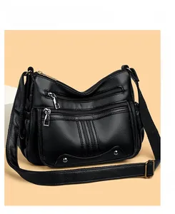Détail du sac bandoulière en cuir noir grainé avec plusieurs poches zippées et boucles