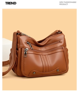 Détail du cuir grainé marron et des poches à fermetures éclair multiples sur le sac bandoulière