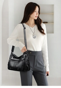 Détail d'un sac bandoulière noir en cuir grainé avec fermetures éclair argentées