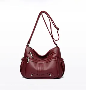 Détail frontal du sac bandoulière bordeaux multi-poches avec texture cuir grainé