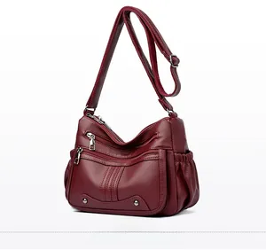 Vue latérale du sac à bandoulière en cuir rouge foncé avec plusieurs poches zippées