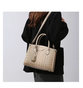 Λεπτομέρεια υφής κροκόδειλου σε μπεζ τσάντα με λαβή και δερμάτινη λεπτομέρεια λογότυπου