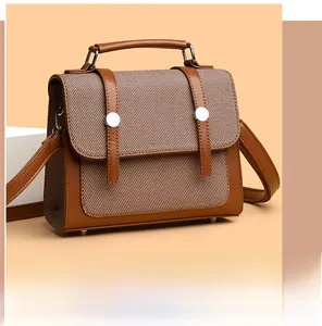Dettaglio di borsa in pelle marrone e tela con fibbie argentate su sfondo beige caldo