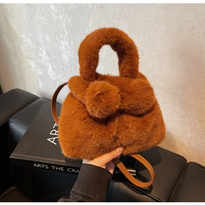 Detail showing plush dark brown faux fur texture and round handle of the bucket bag