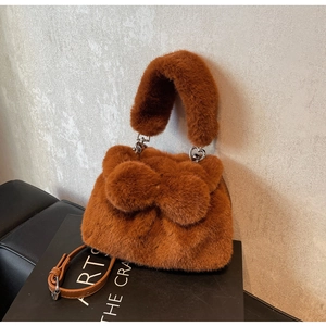 Detail of caramel faux fur bucket bag with large plush bow and detachable PU strap