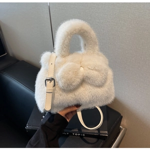 Detail of white faux fur bucket bag featuring a large plush bow and leather strap