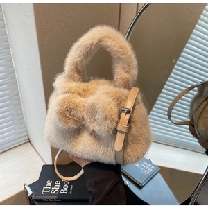 Detail of plush faux fur bucket bag in beige featuring a decorative bow and leather strap