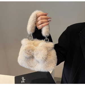 Close-up of beige plush bucket bag with bow detail and silver heart shaped metal rings
