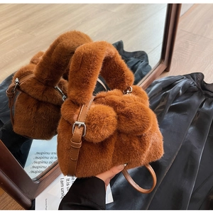 Detail of caramel plush bucket bag featuring brown faux fur texture and silver buckle strap