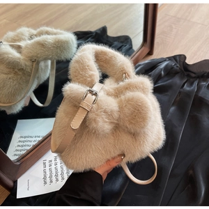 Close-up of fluffy faux fur handbag in cream beige with slim leather strap and silver buckle