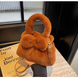 Detail of plush brown faux fur handbag with decorative pom-poms and leather strap