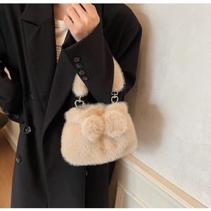 Detail of plush beige bucket bag featuring a 3D bow and silver heart-shaped metal buckle