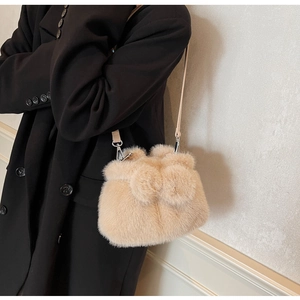 Detailed plush bucket bag with soft faux fur texture and decorative pom-poms on shoulder