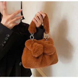 Detail of plush brown bucket bag featuring a soft faux fur bow and silver heart rings