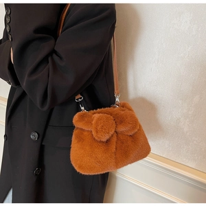 Detail of brown fuzzy bucket bag with plush bow and thin leather shoulder strap