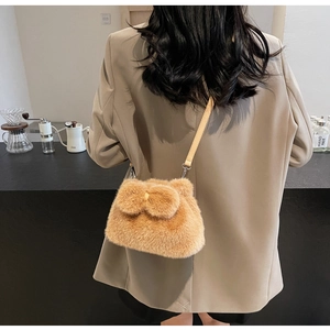 Close-up of brown plush bucket bag with a decorative 3D bow and slim leather strap