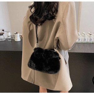 Detail of black plush bucket bag with silver metal chain on casual khaki blazer