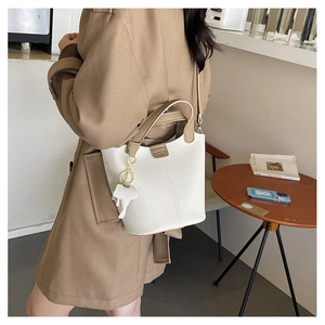 Detalle de bolso cubo en cuero litchi blanco con asa caqui y colgante de elefante