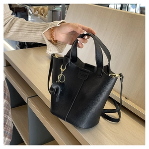 Detalle de bolso cubo negro de grano de lichi con relieve y colgante de elefante