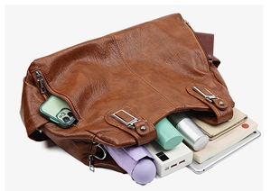 Grande borsa marrone con interno spazioso contenente oggetti essenziali e accessori vari