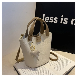 Primer plano del bolso tipo cubo blanco crema con textura de lichi y colgante