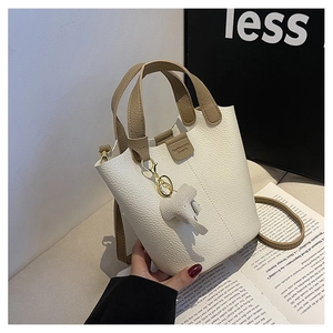 Detalle de un bolso cubo blanco crema con textura de piel granulada y colgante de elefante