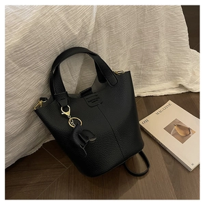 Detalle de bolso tipo cubo de cuero granulado negro con herrajes dorados y dije