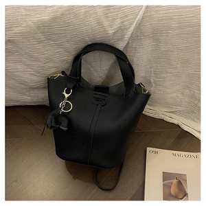 Detalle del bolso tipo cubo negro con grano de lichi, herrajes dorados y amuleto de elefante