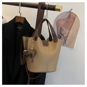 Detalle de bolso cubo beige de cuero granulado con colgante de caballo en percha