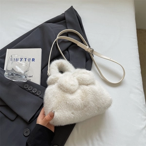 Plush white faux fur bow-shaped bucket bag with an adjustable leather shoulder strap