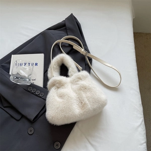 White faux fur cloud bucket bag with adjustable leather strap on a stylish grey blazer