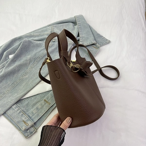 Bolso tipo cubo en cuero marrón oscuro con asa superior y correa de hombro ajustable