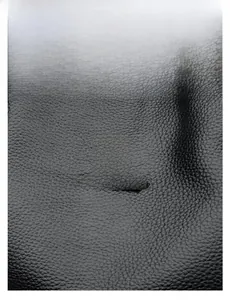 Macro view of black litchi grain leather bag with a silver kangaroo metal logo detail